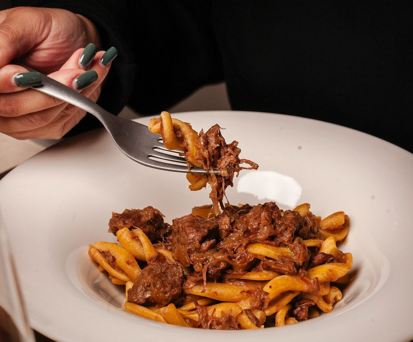 Una persona tiene una forchetta sopra una ciotola di pasta
