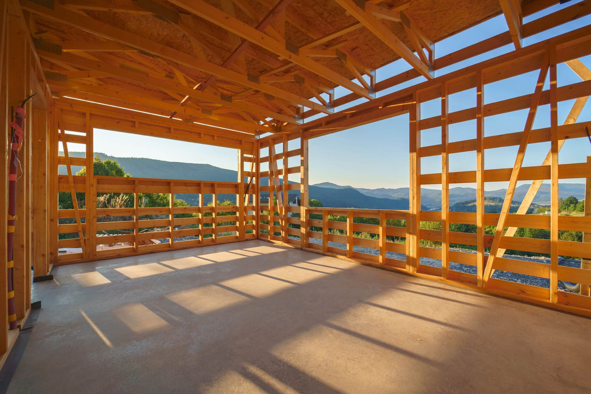 Wooden frame of a building under construction, with a view of mountains through the openings.