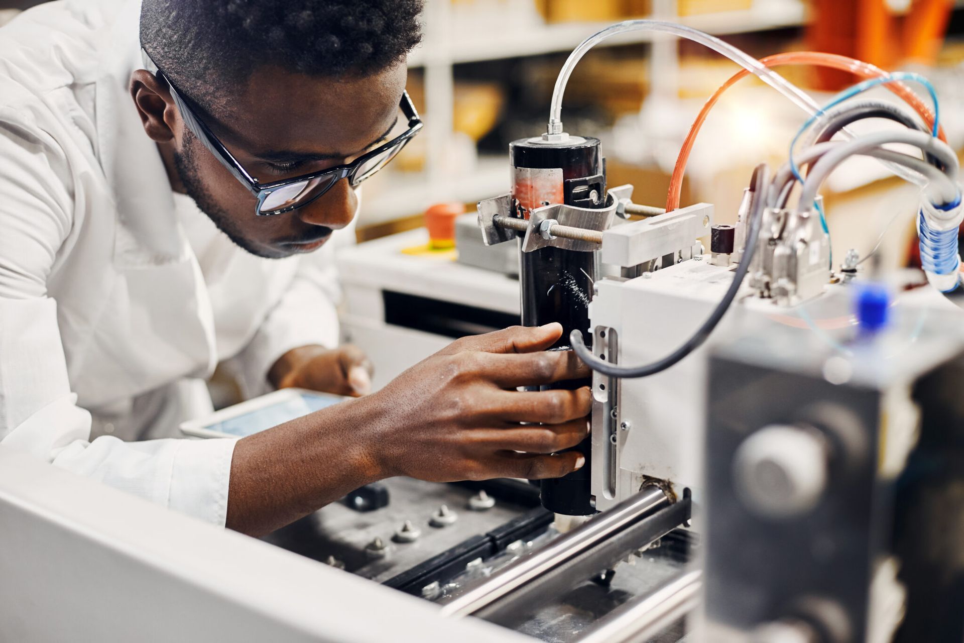 Man in glasses and lab coat working on machinery in a lab.