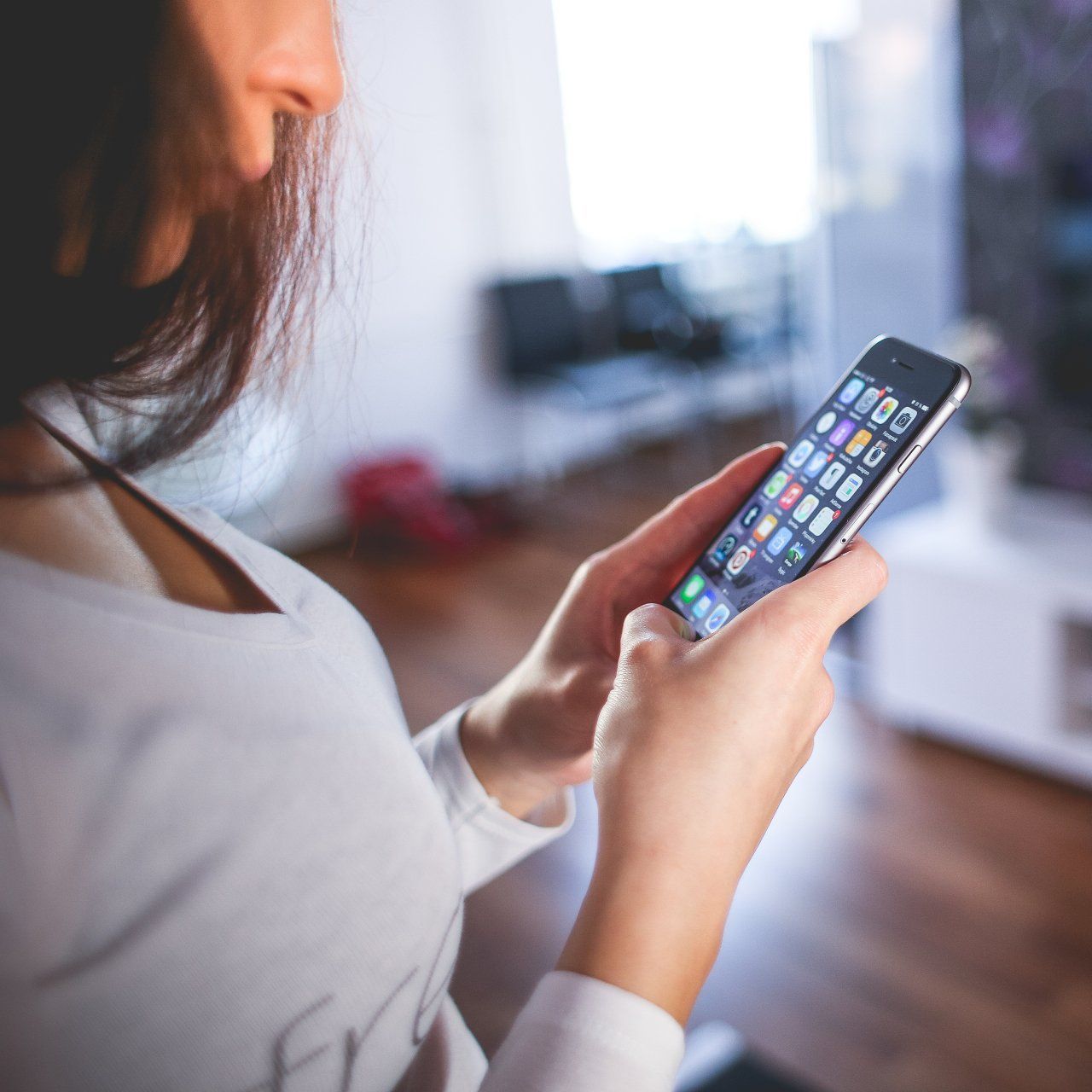 A woman in a white shirt is holding a cell phone in her hand