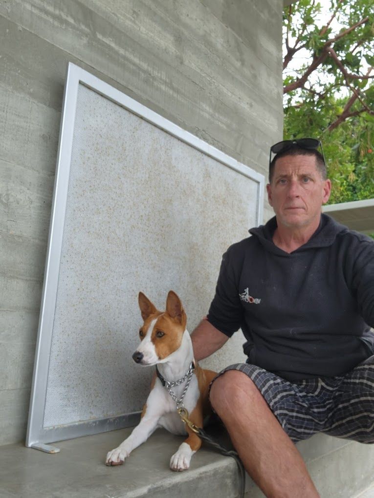 Rich Rosen, owner of Dockside Dog Training, and a dog seated outdoors next to a framed board. The dog is light-colored.