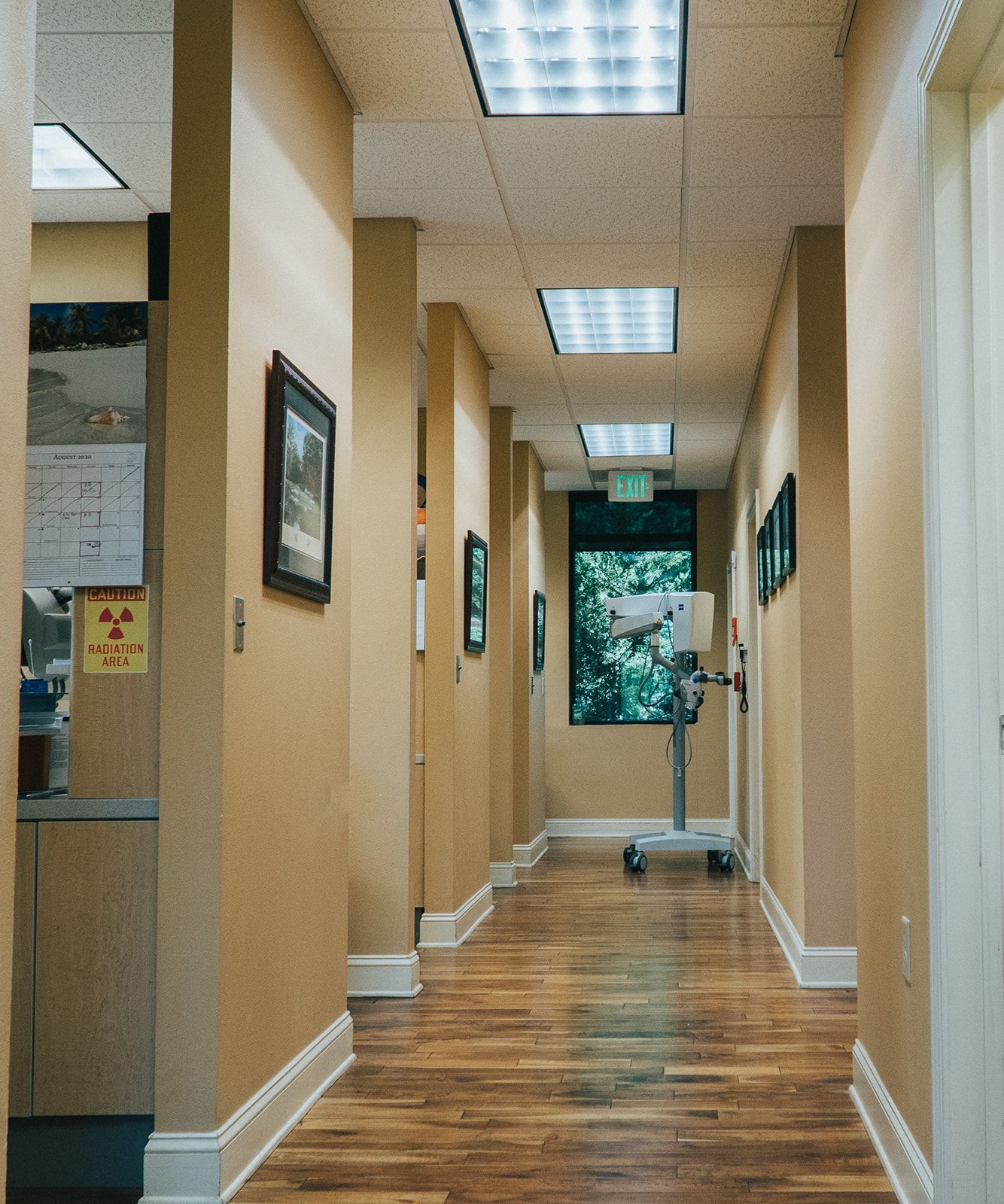 Hallway with light beige walls, wooden floor, and framed pictures.