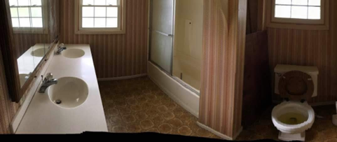 Bathroom with two sinks, a toilet, and a shower/tub, wallpaper and a window.