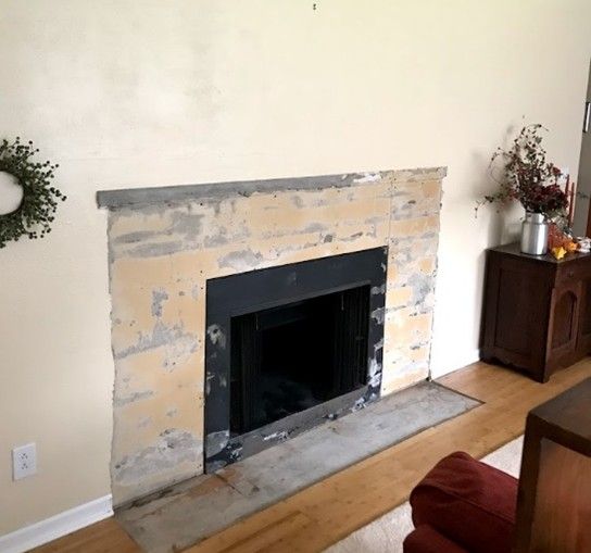 Fireplace with exposed stone surround, black firebox, on a wood floor.