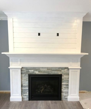 White fireplace with shiplap feature, gray stone, and a black firebox.