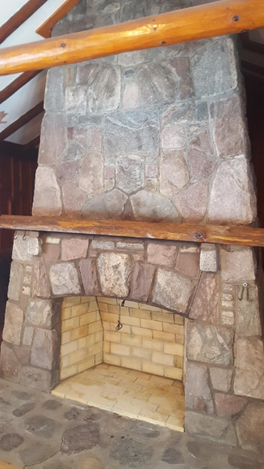 Stone fireplace with wooden mantle and light brick firebox.