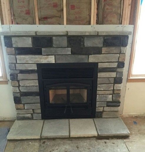 Stone fireplace with black insert, gray stone surround, and wood-framed walls.