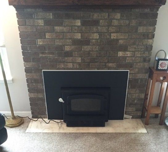 Brick fireplace with a black insert and wood mantel.