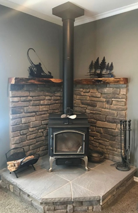 Corner fireplace with a black stove, stone surround, and wood mantle.