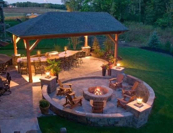 Outdoor patio with stone fireplace, seating area, and cable railing.