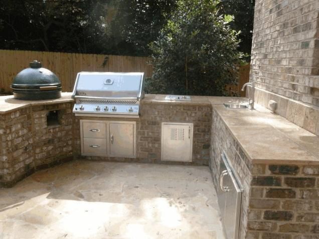 Outdoor kitchen with brick facing, stainless steel appliances, and countertop, on a concrete patio.