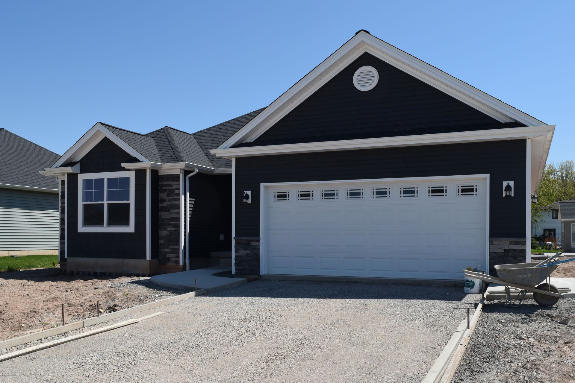Modern single-story dark blue house with white trim and a two-car garage in a gravel driveway.