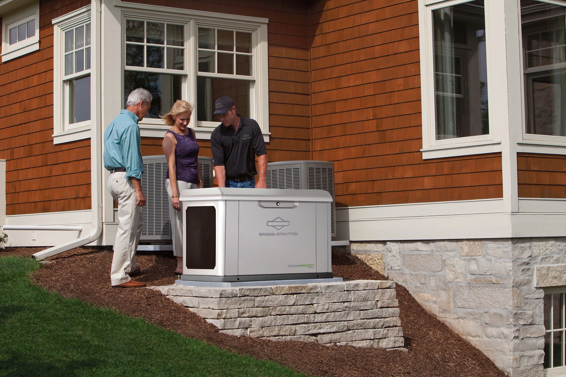 A man and a woman are standing in front of a house looking at an air conditioner.