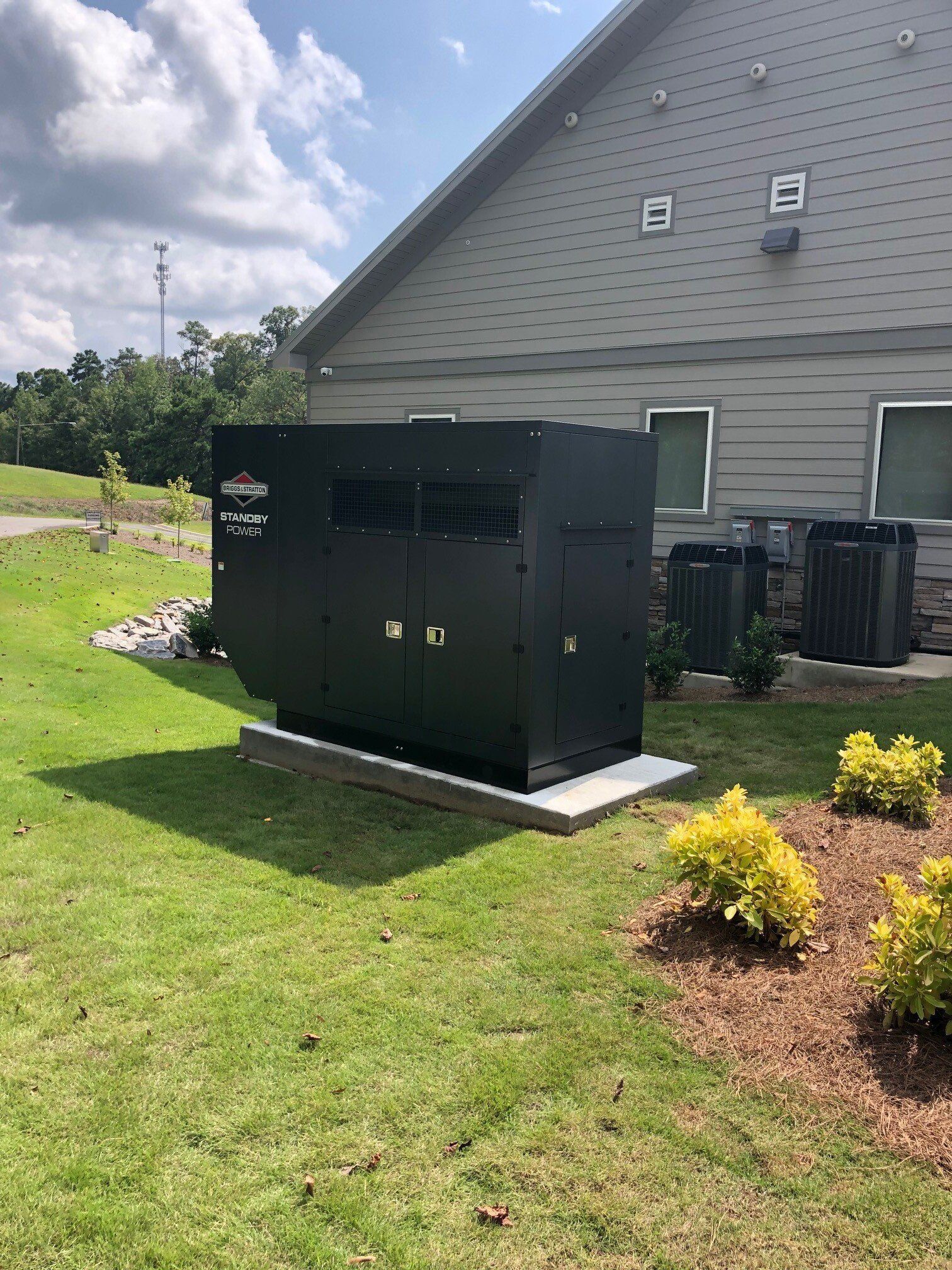 A large black box is sitting in the grass in front of a building.