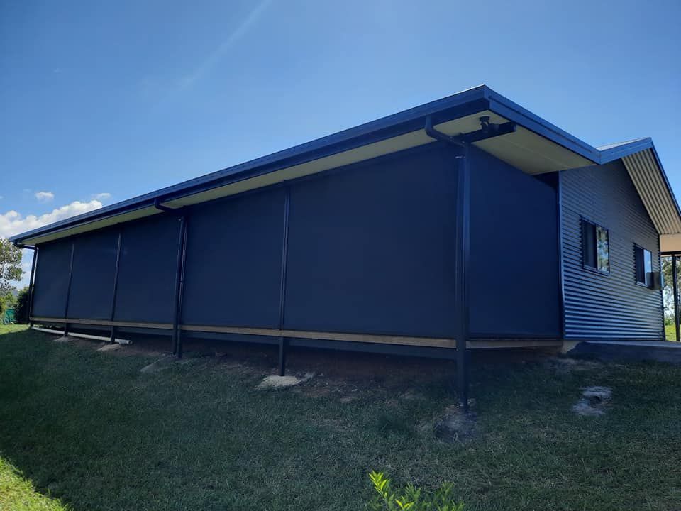 Large Black House is Sitting on Top of a Lush Green Field — Tropical Shade Blinds in Brinsmead, QLD