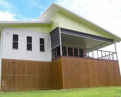 Large White House With a Wooden Fence Around It — Tropical Shade Blinds in Brinsmead, QLD