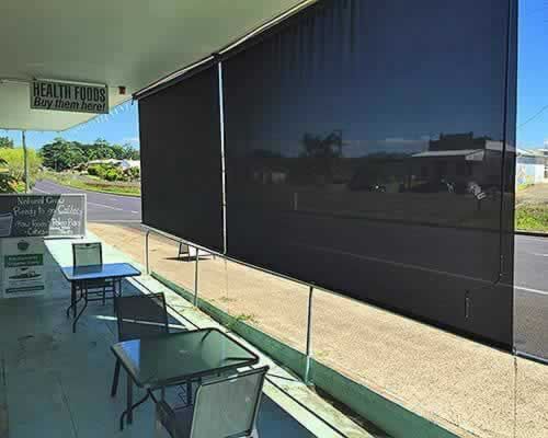 Patio With a Table and Chairs and a Black Awning — Tropical Shade Blinds in Brinsmead, QLD