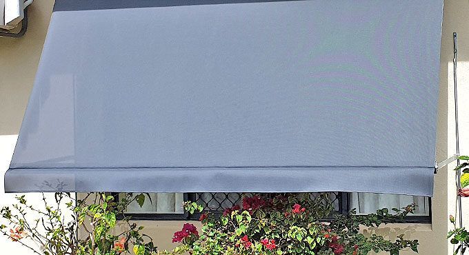 Gray Awning is Hanging Over a Window on a Building — Tropical Shade Blinds in Brinsmead, QLD