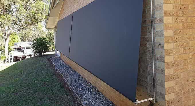 Large Black Wall is on the Side of a Brick Building — Tropical Shade Blinds in Brinsmead, QLD