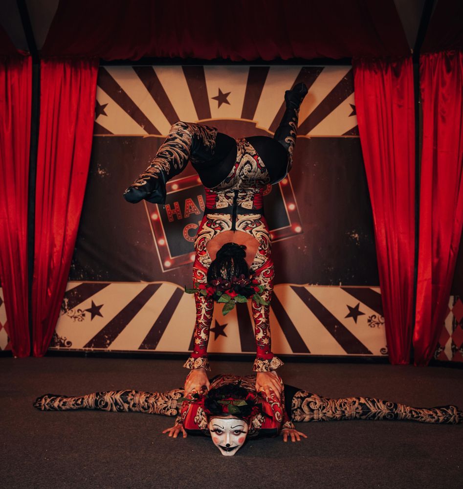 A man is doing a handstand in front of a sign that says happy circus