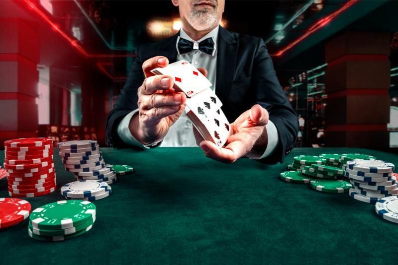 A man in a suit and bow tie is playing poker in a casino.