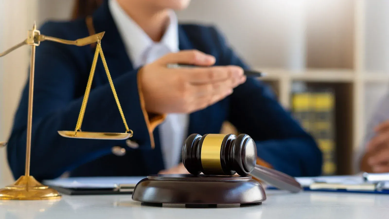 A judge is sitting at a desk with a gavel and scales of justice.