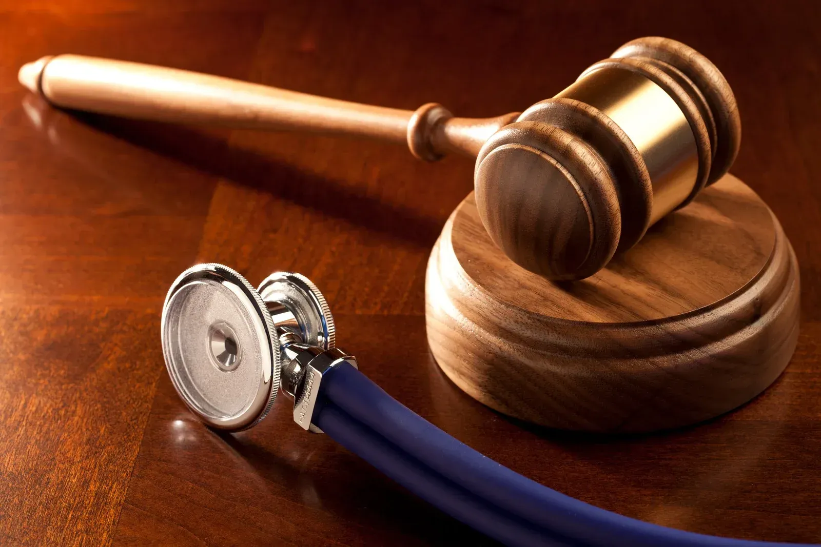 A wooden gavel and a stethoscope on a wooden table