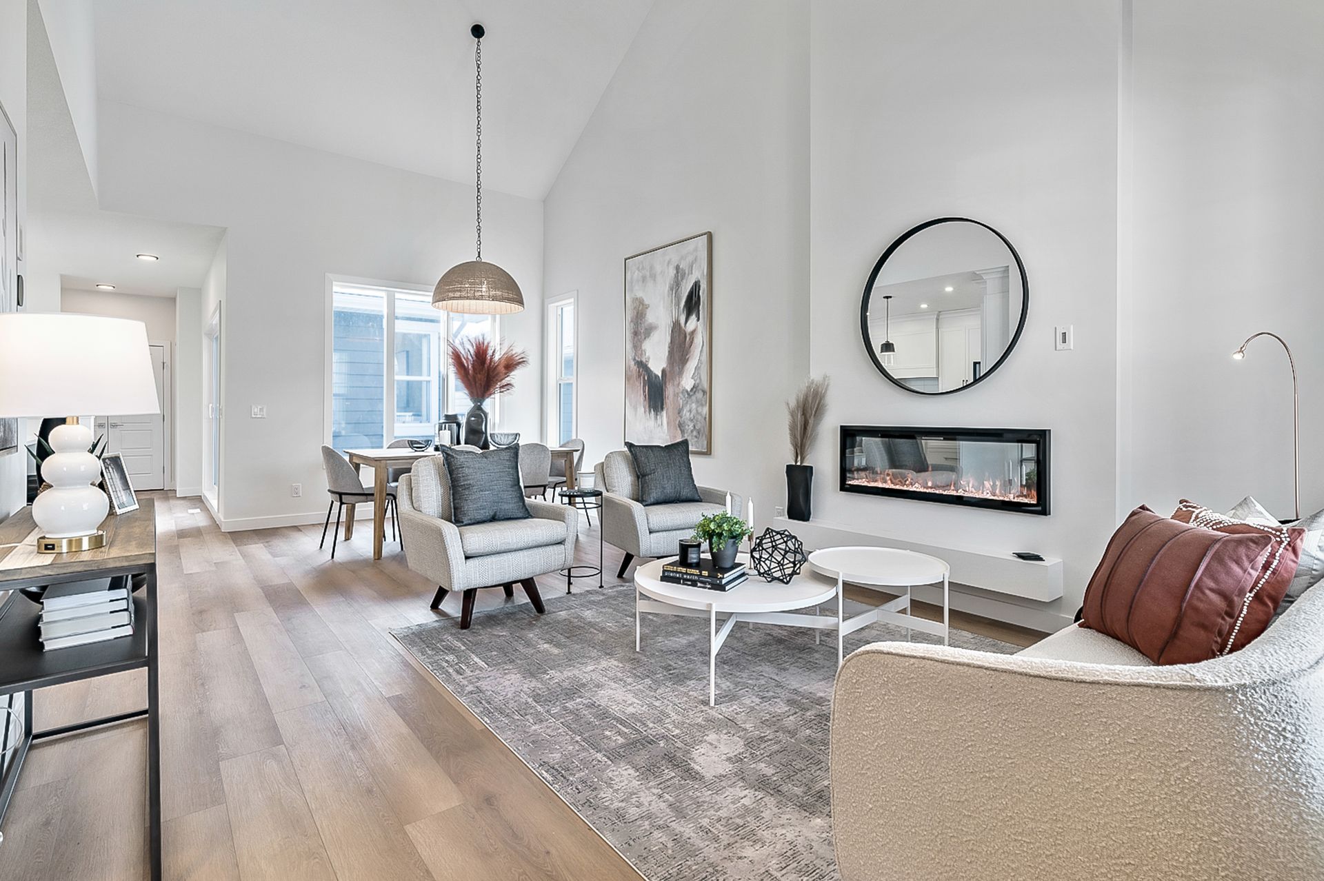 Bright, modern living room with white walls, fireplace, light wood floors, and furniture.