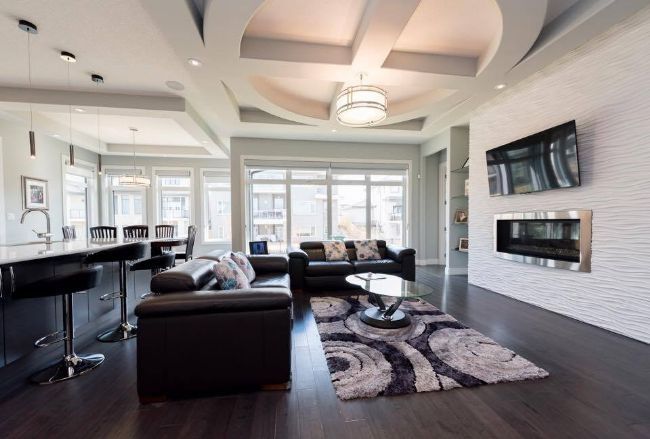 Living room: black leather sofas, white textured wall with TV and fireplace, modern ceiling.