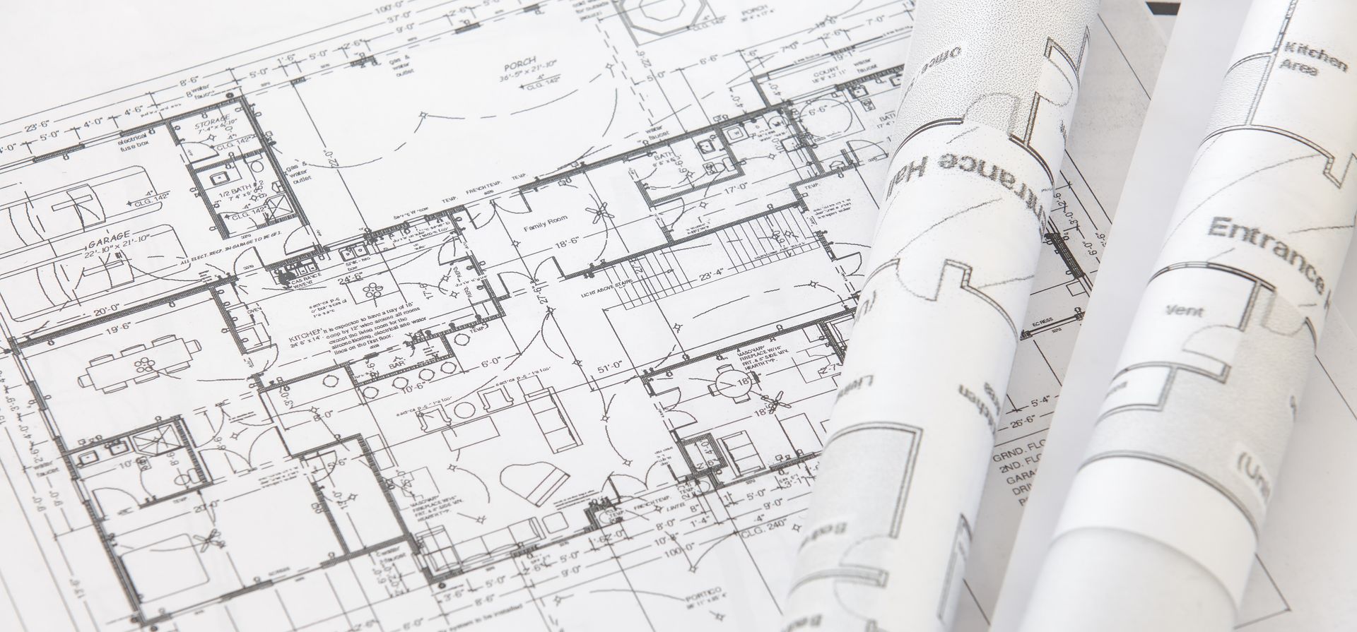 Architectural blueprints, rolled and laid out, showcasing a detailed building plan.