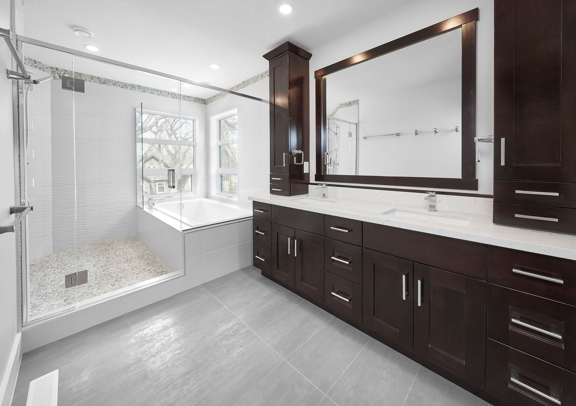 Modern bathroom with dark wood vanity, white marble countertop, glass shower, and soaking tub.