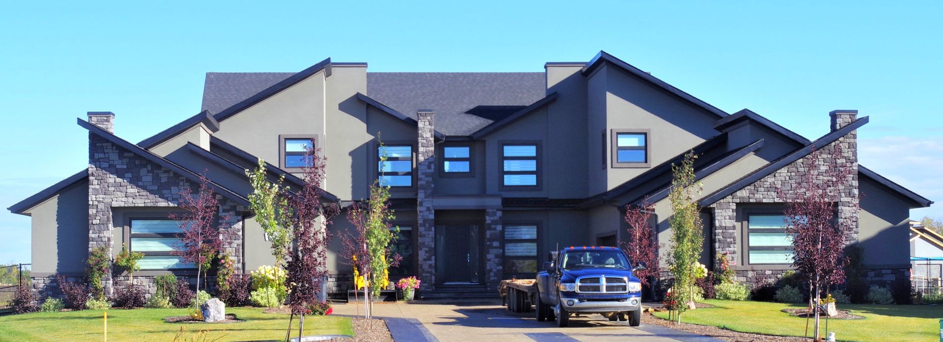 Modern gray house with blue truck in driveway.