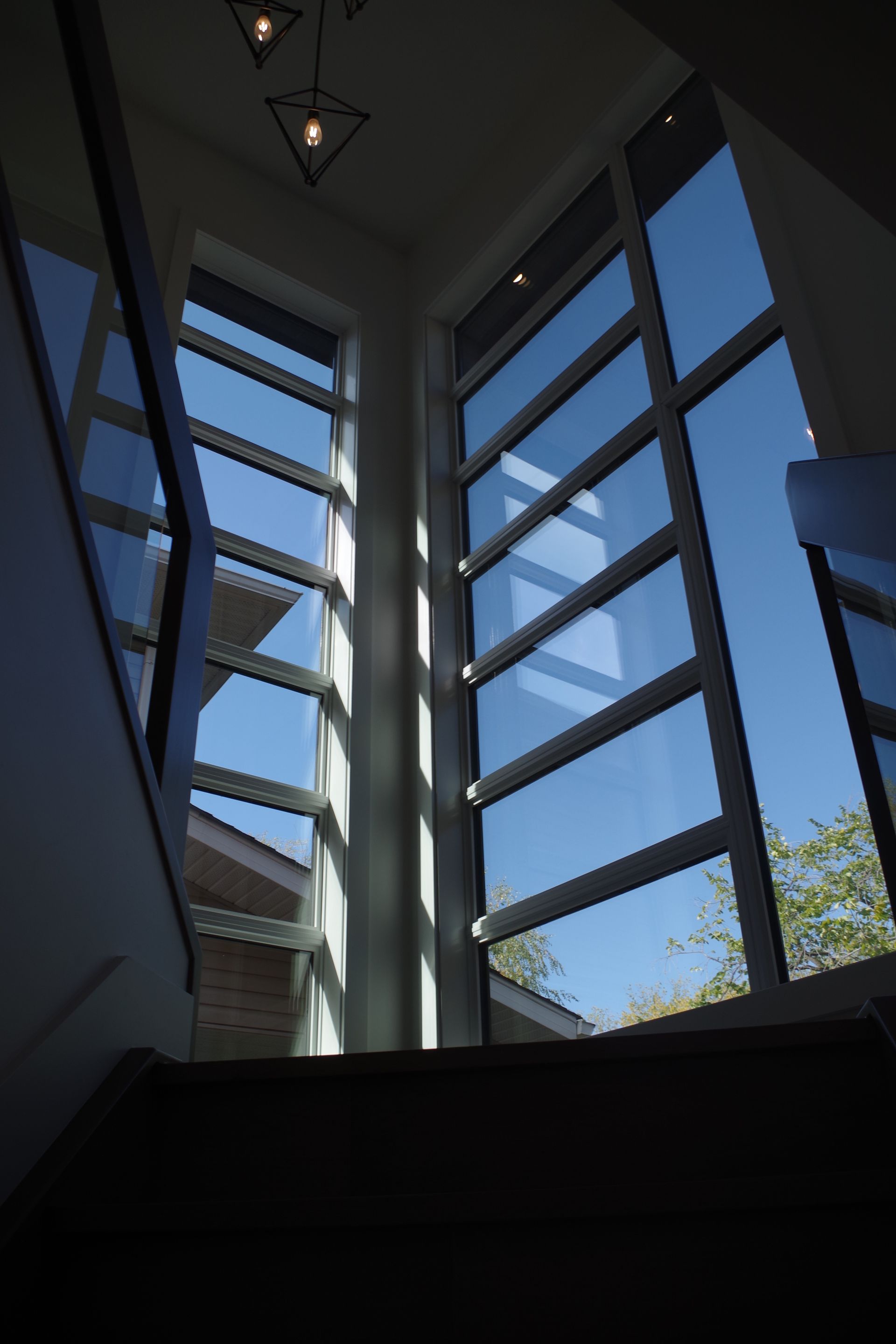 Interior view of staircase with large windows showing a bright blue sky.
