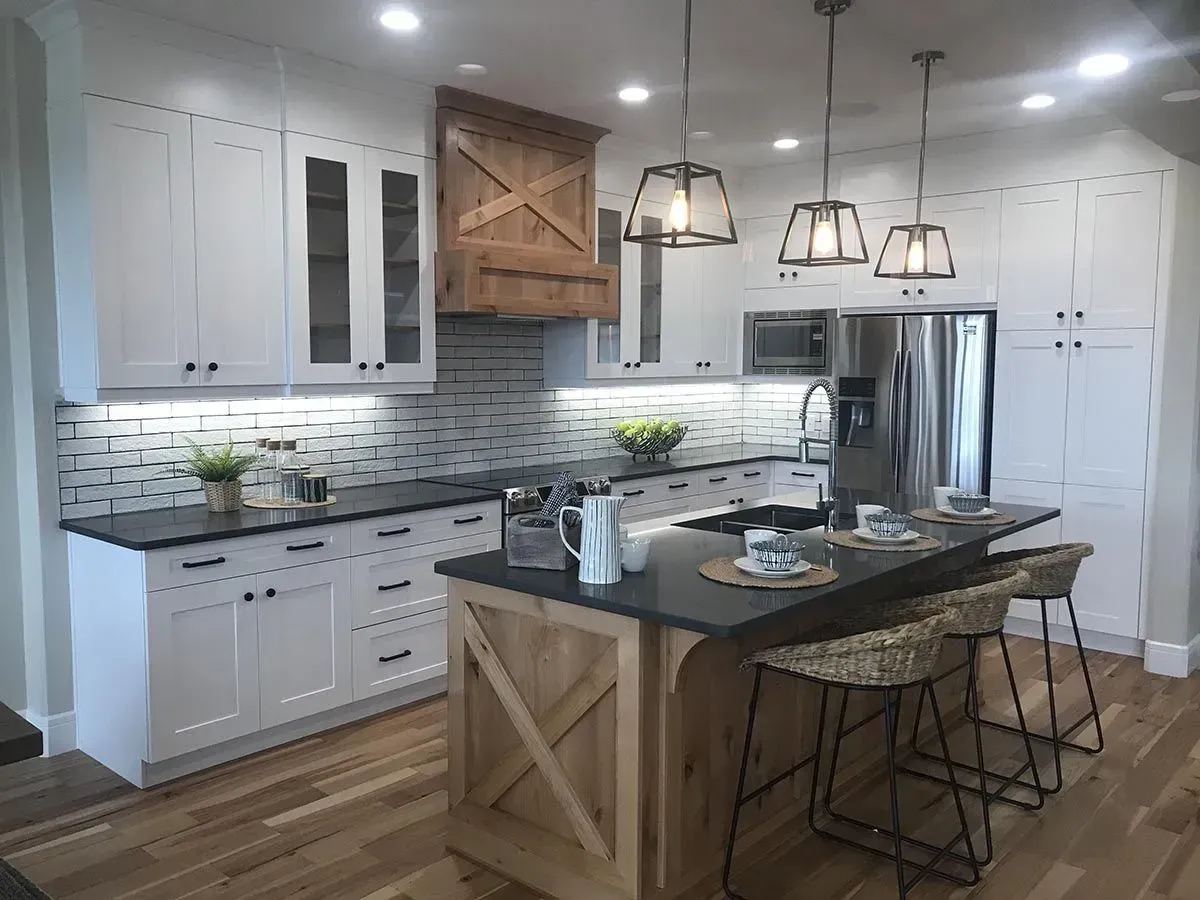 Modern farmhouse kitchen with white cabinets, wooden island, and black countertops.
