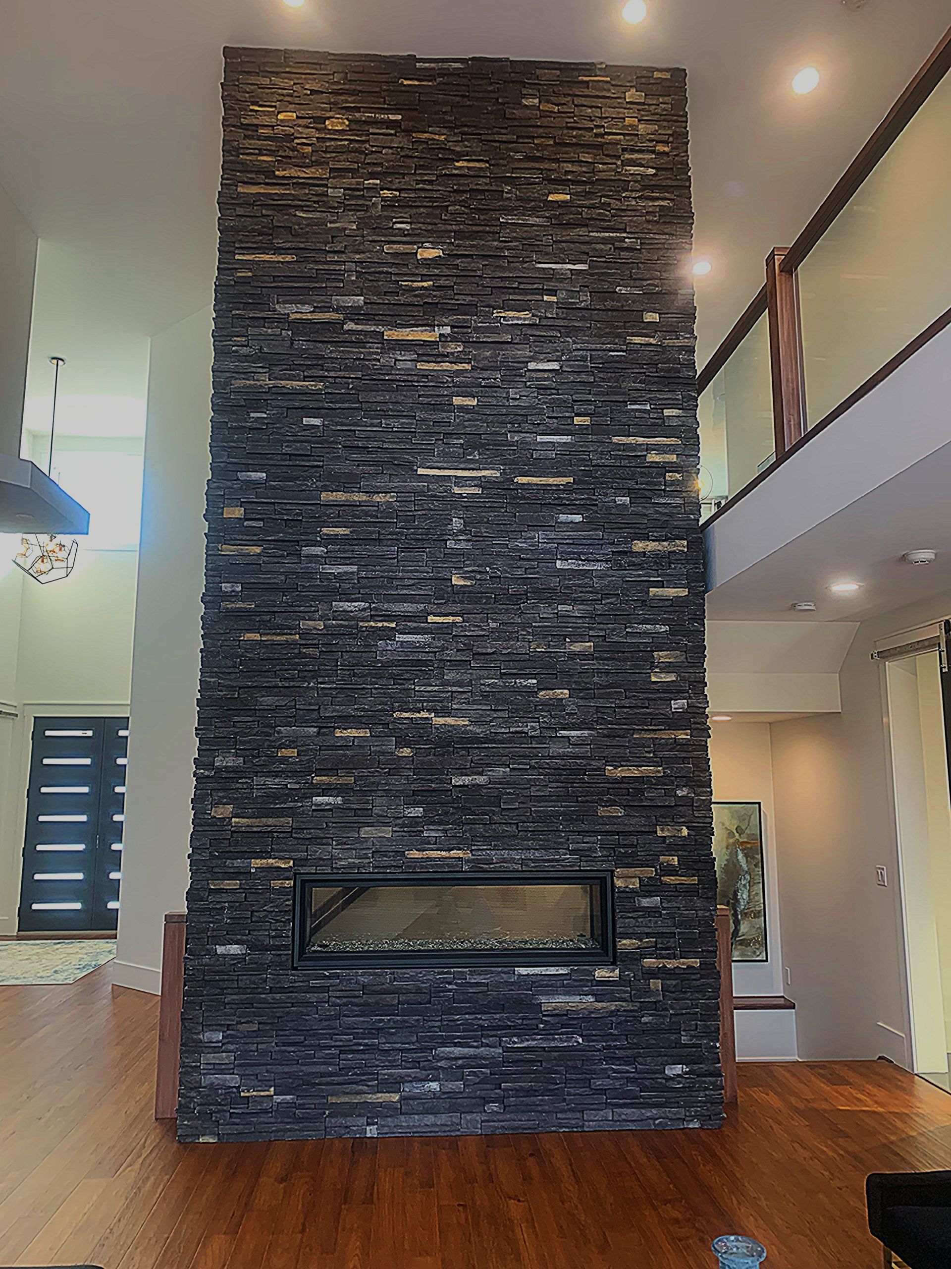 A tall, dark stone fireplace reaching to the ceiling in a modern home.