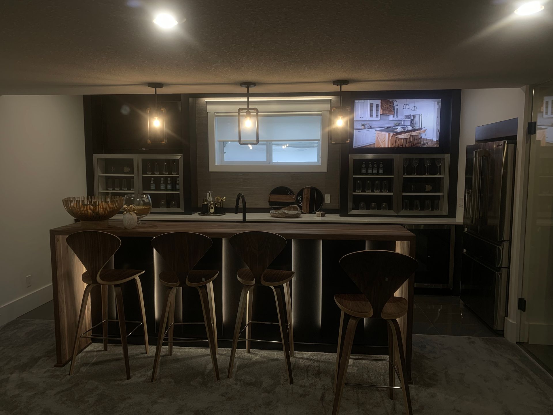 Bar area with wood bar, stools, wine fridges, TV, and a window.