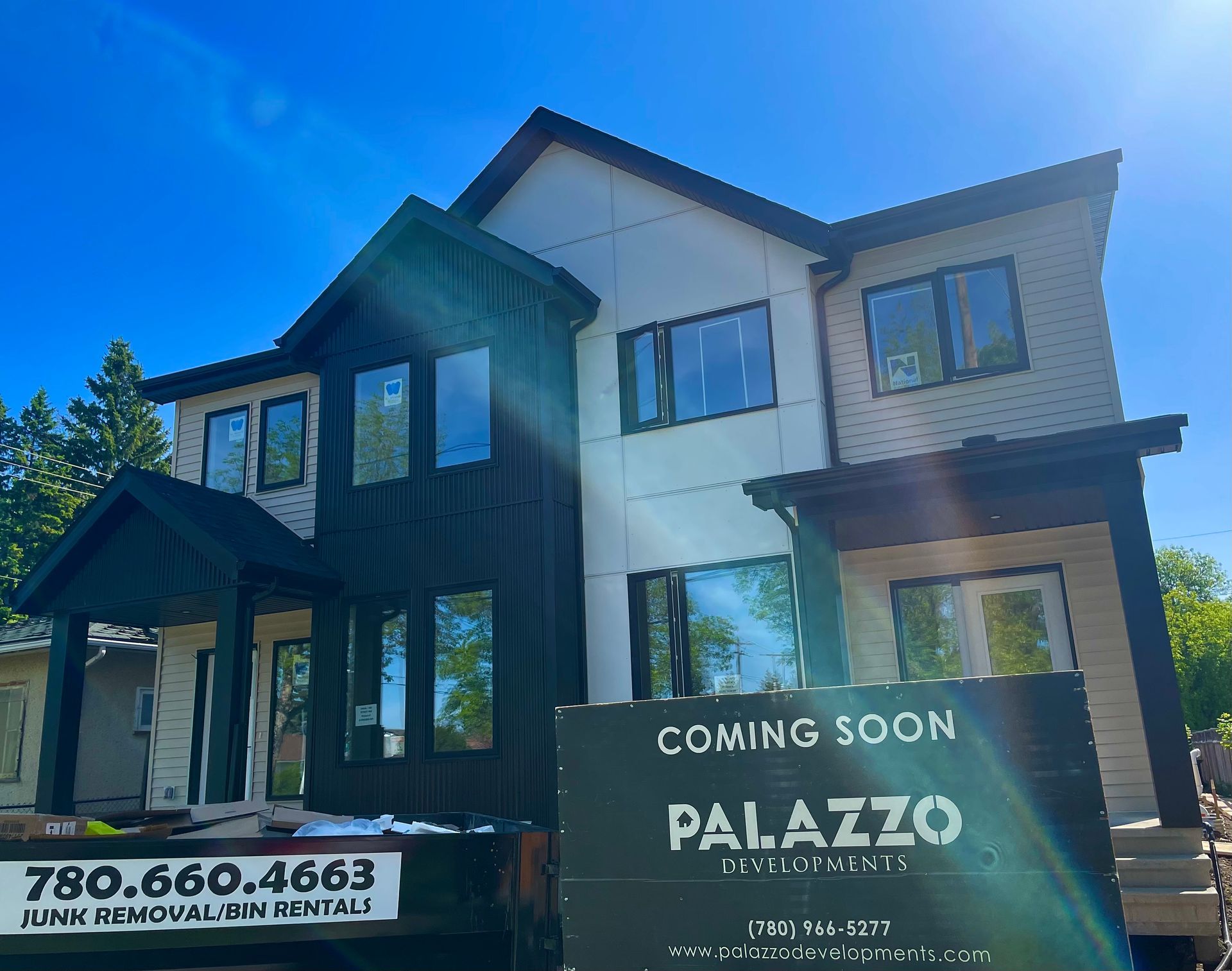 Modern two-story home under construction with black and beige siding;