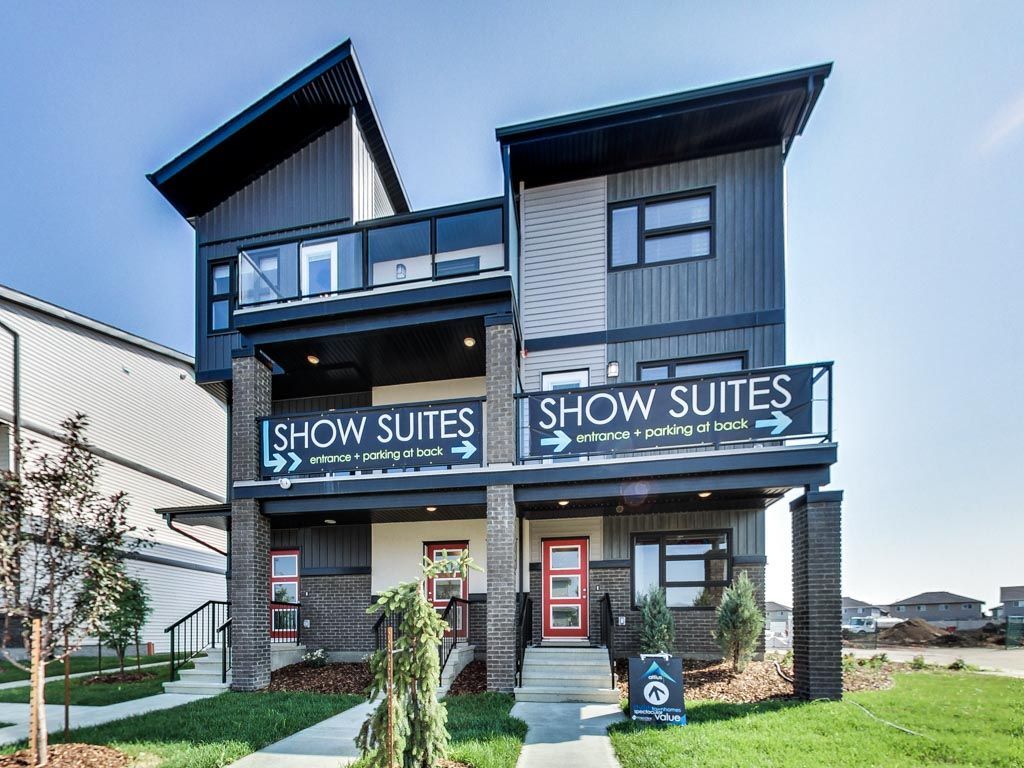 Modern show suites building with signs, red door, and dark gray siding.