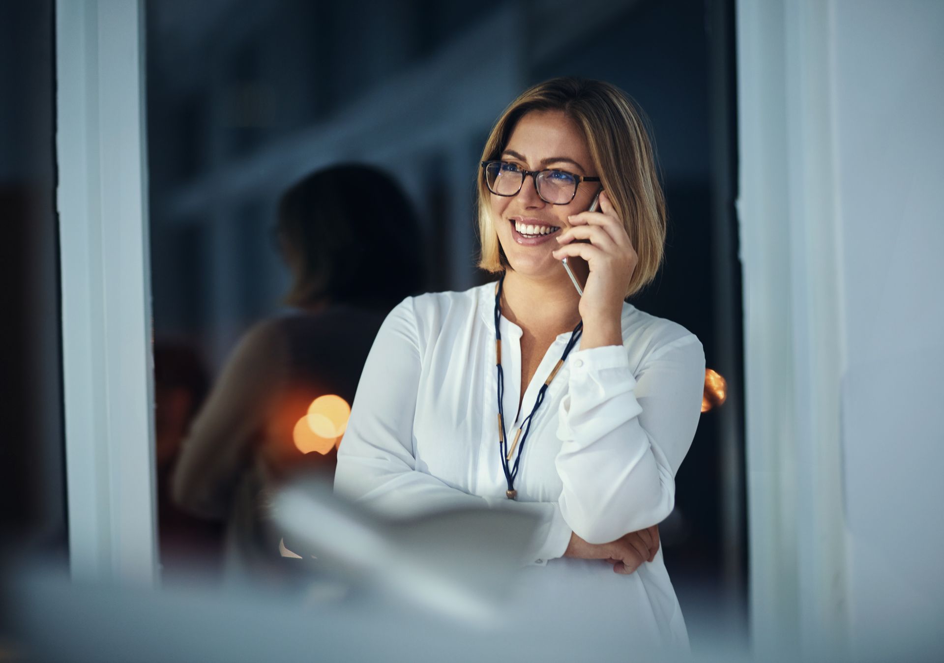 A woman is talking on a cell phone while looking out of a window.