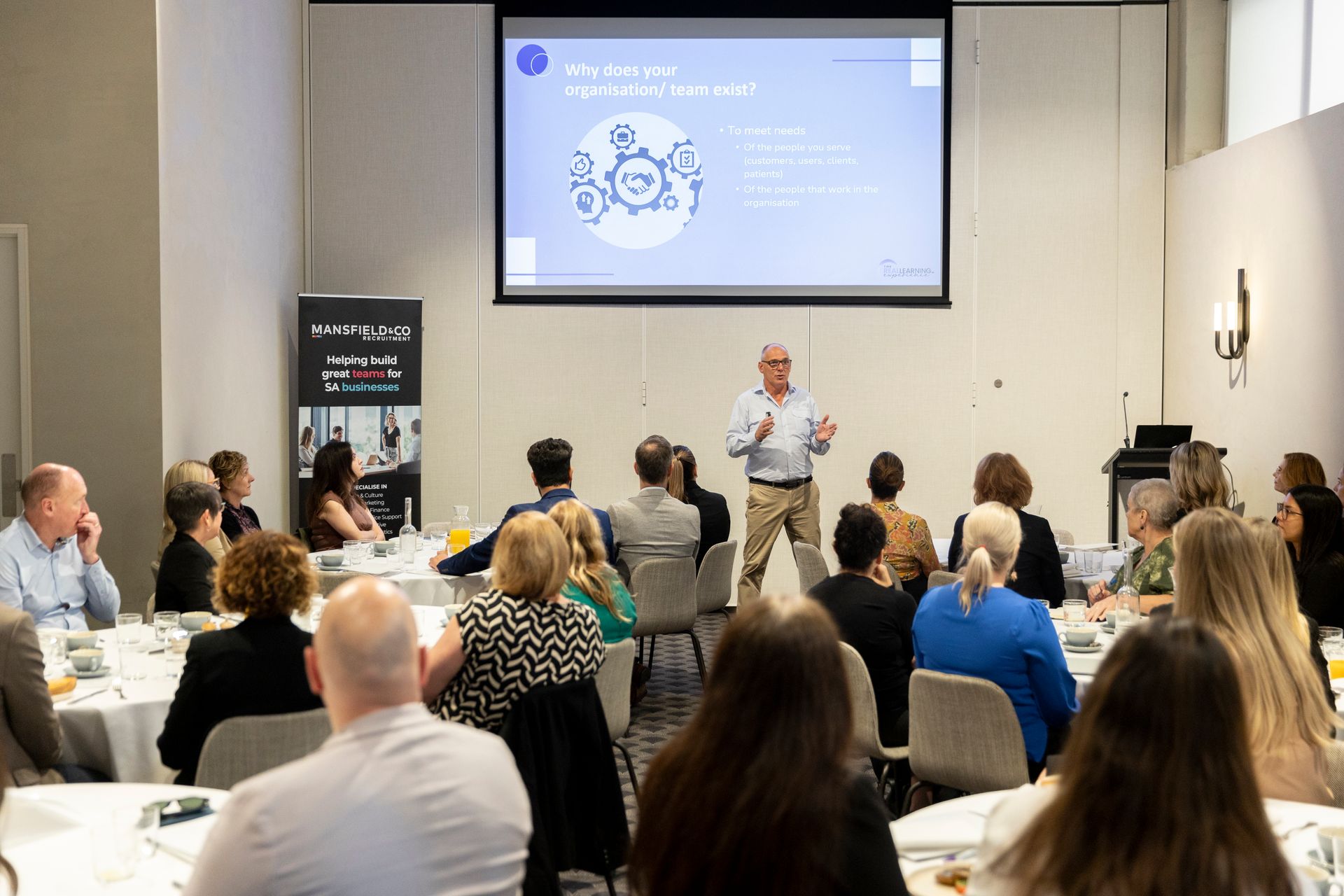 A man is giving a presentation to a group of people in a conference room.