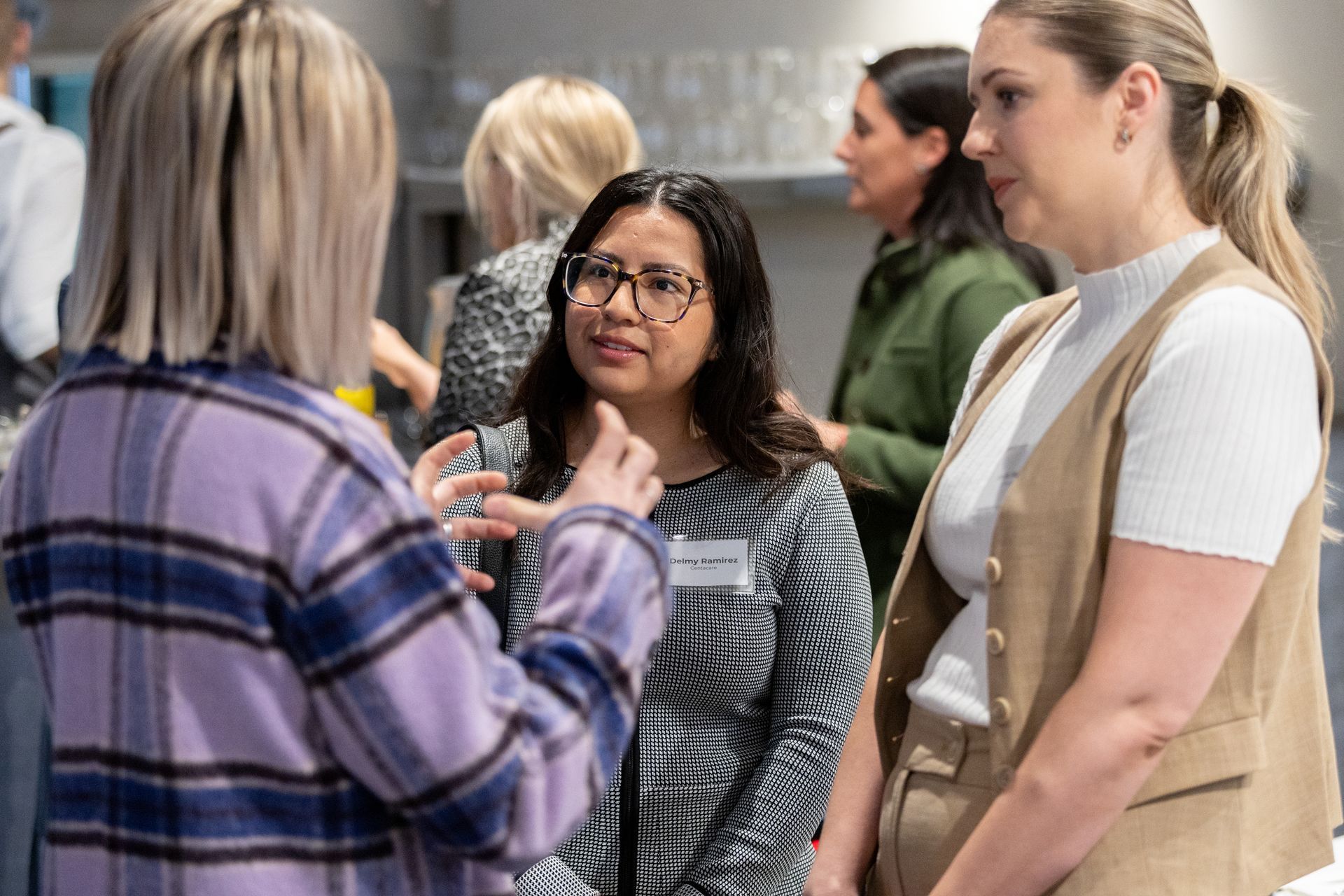 A group of women are standing next to each other talking in a room.