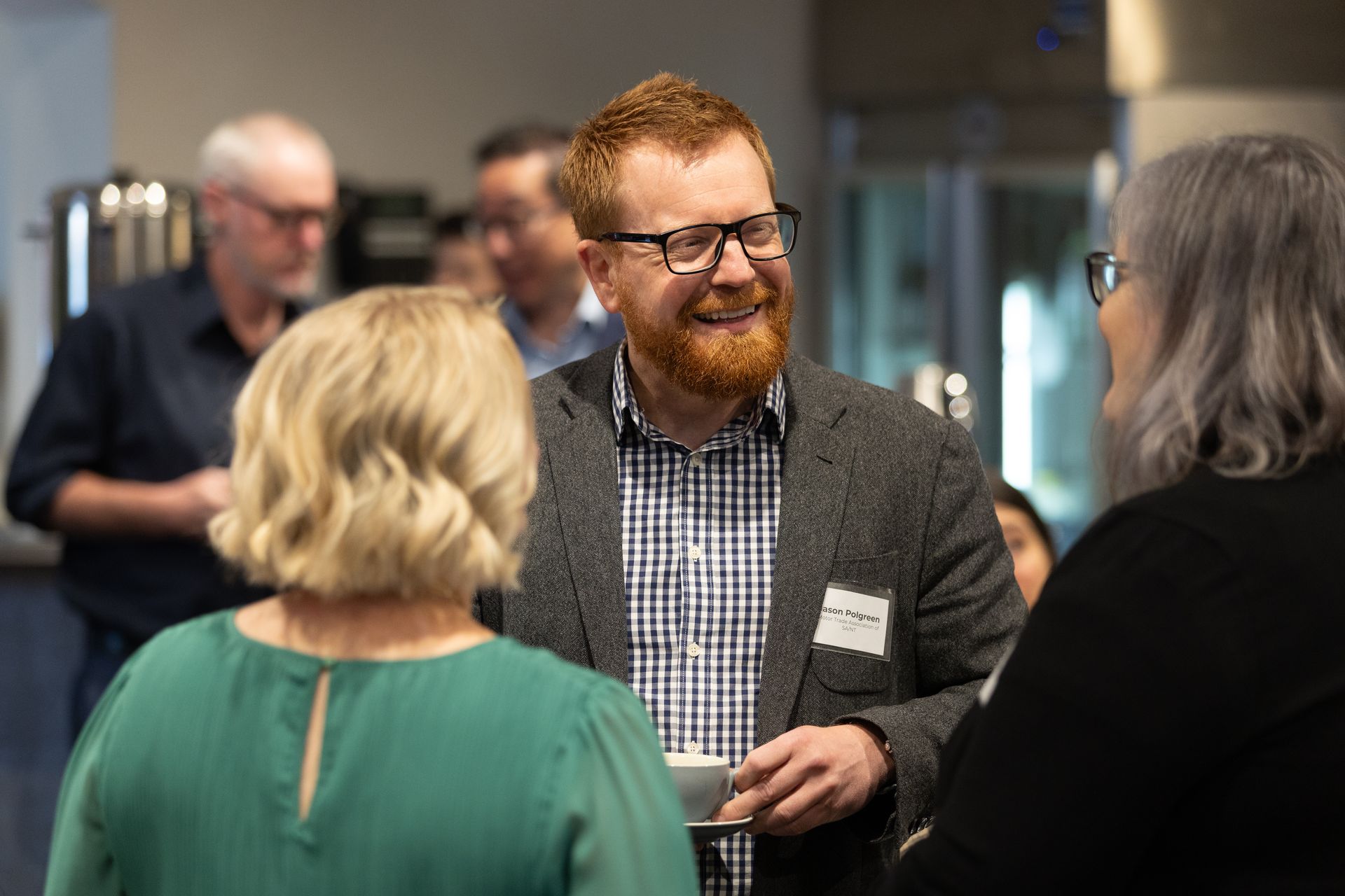 A man with a beard and glasses is talking to two women.