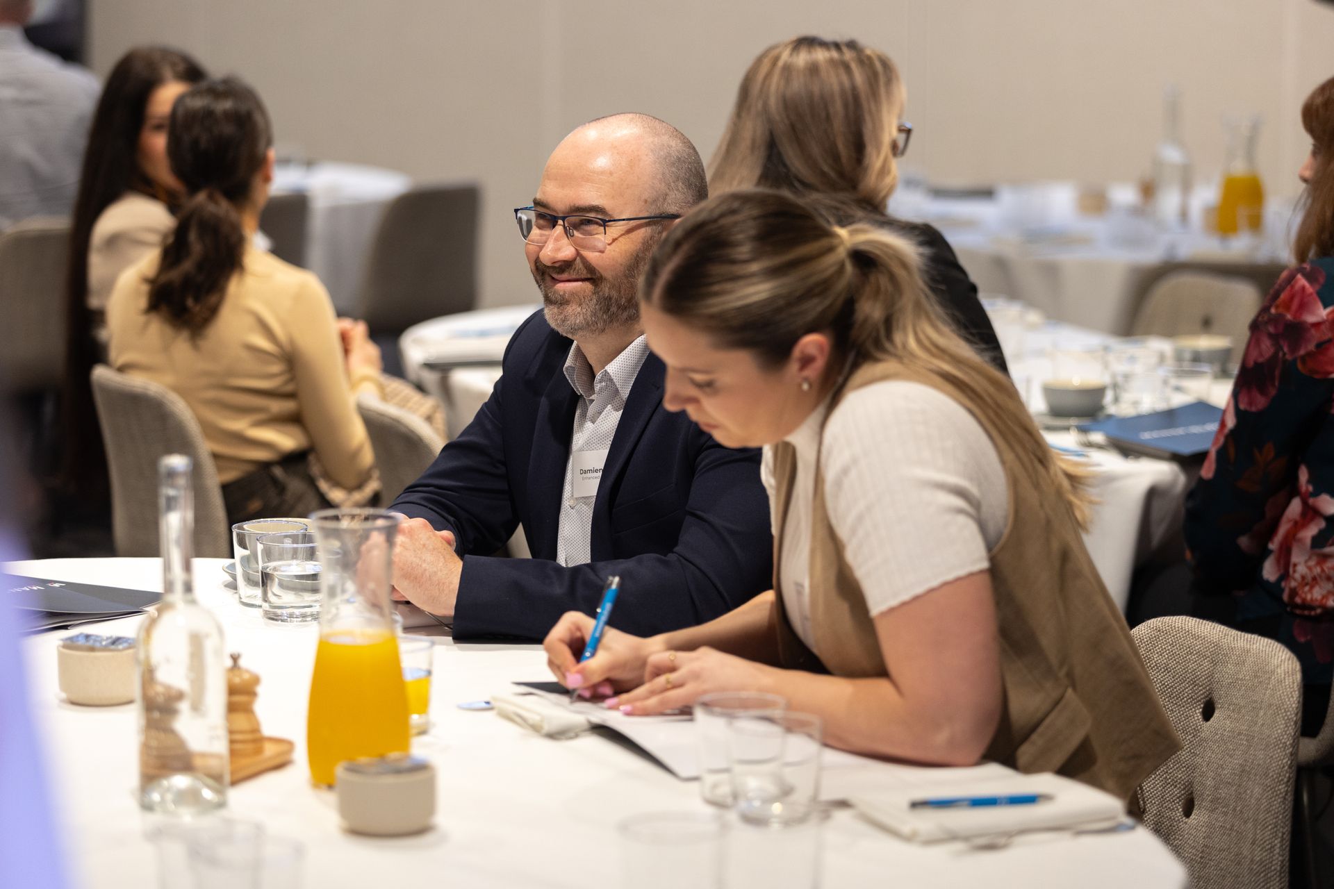 A man and a woman are sitting at a table writing in a notebook.