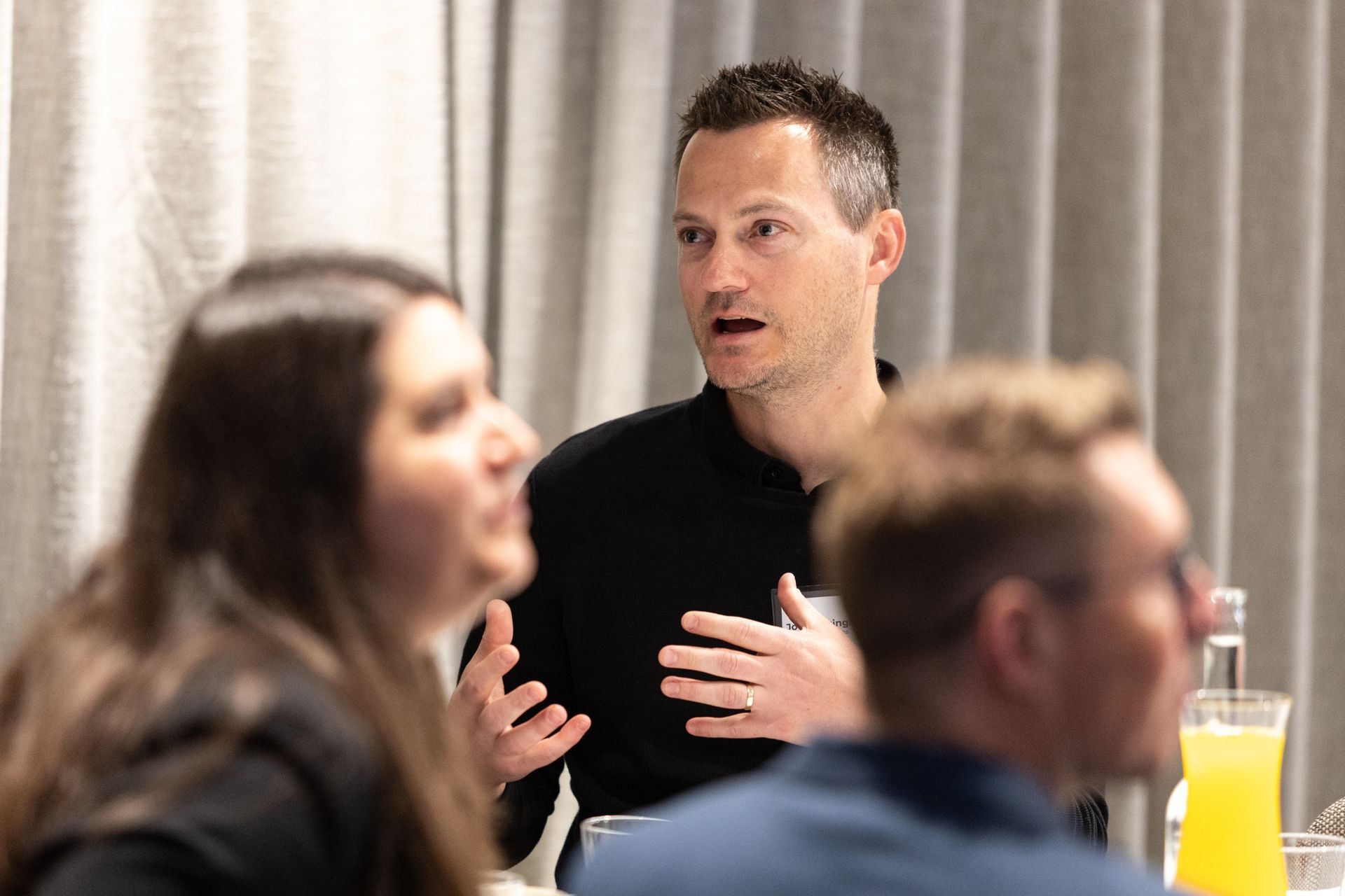 A group of people are sitting at a table talking to each other.
