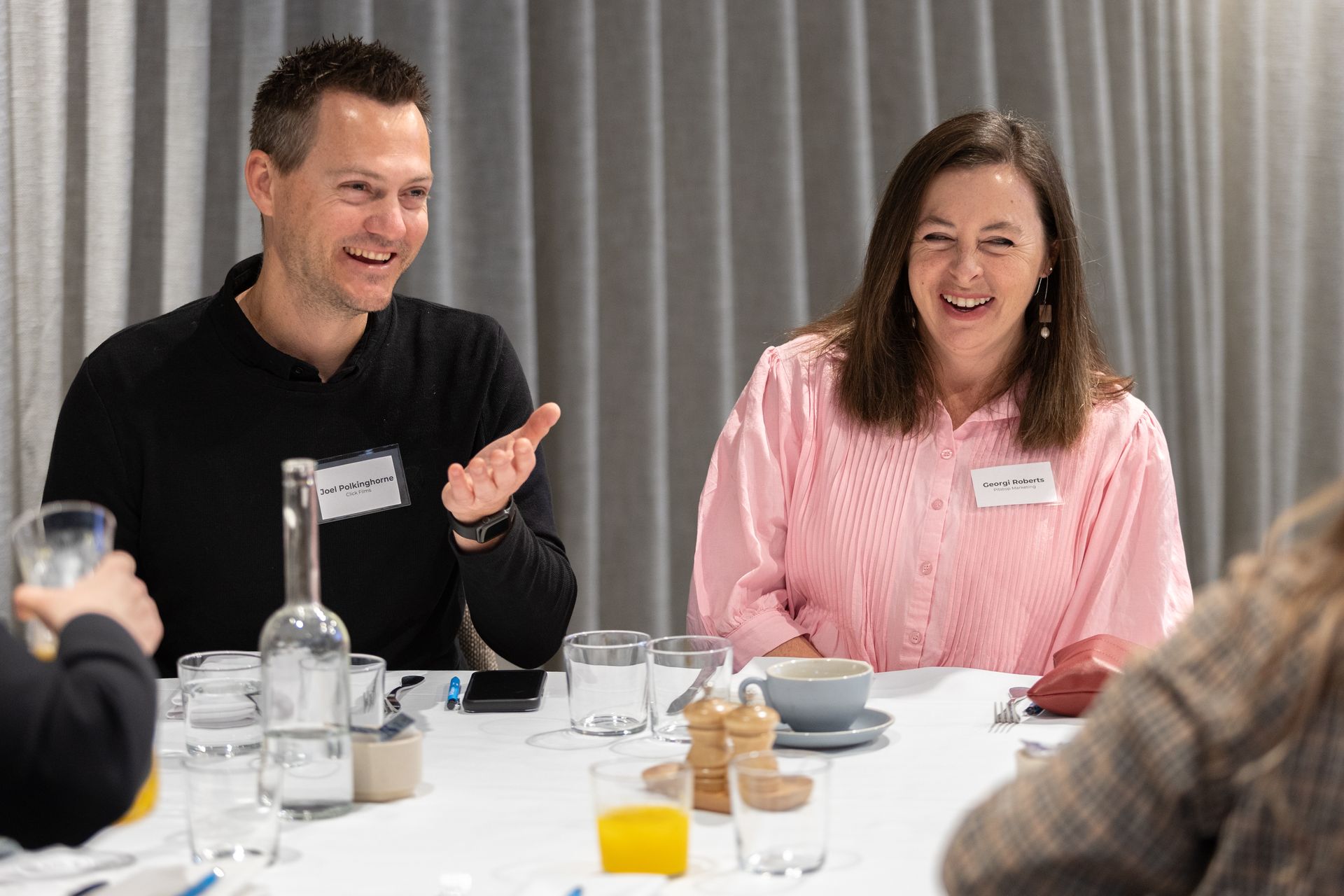 A man and a woman are sitting at a table talking to each other.
