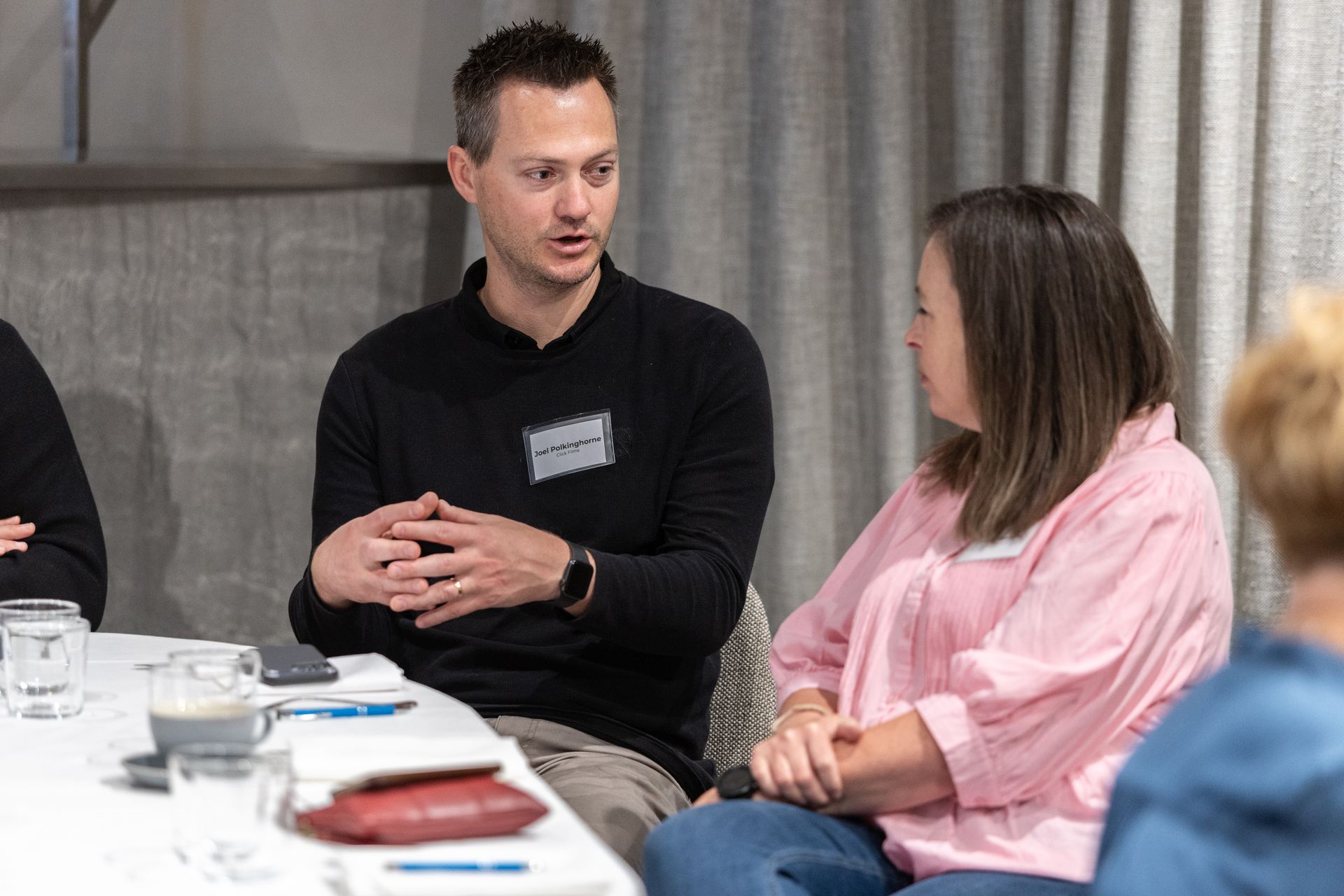 A man and a woman are sitting at a table talking to each other.