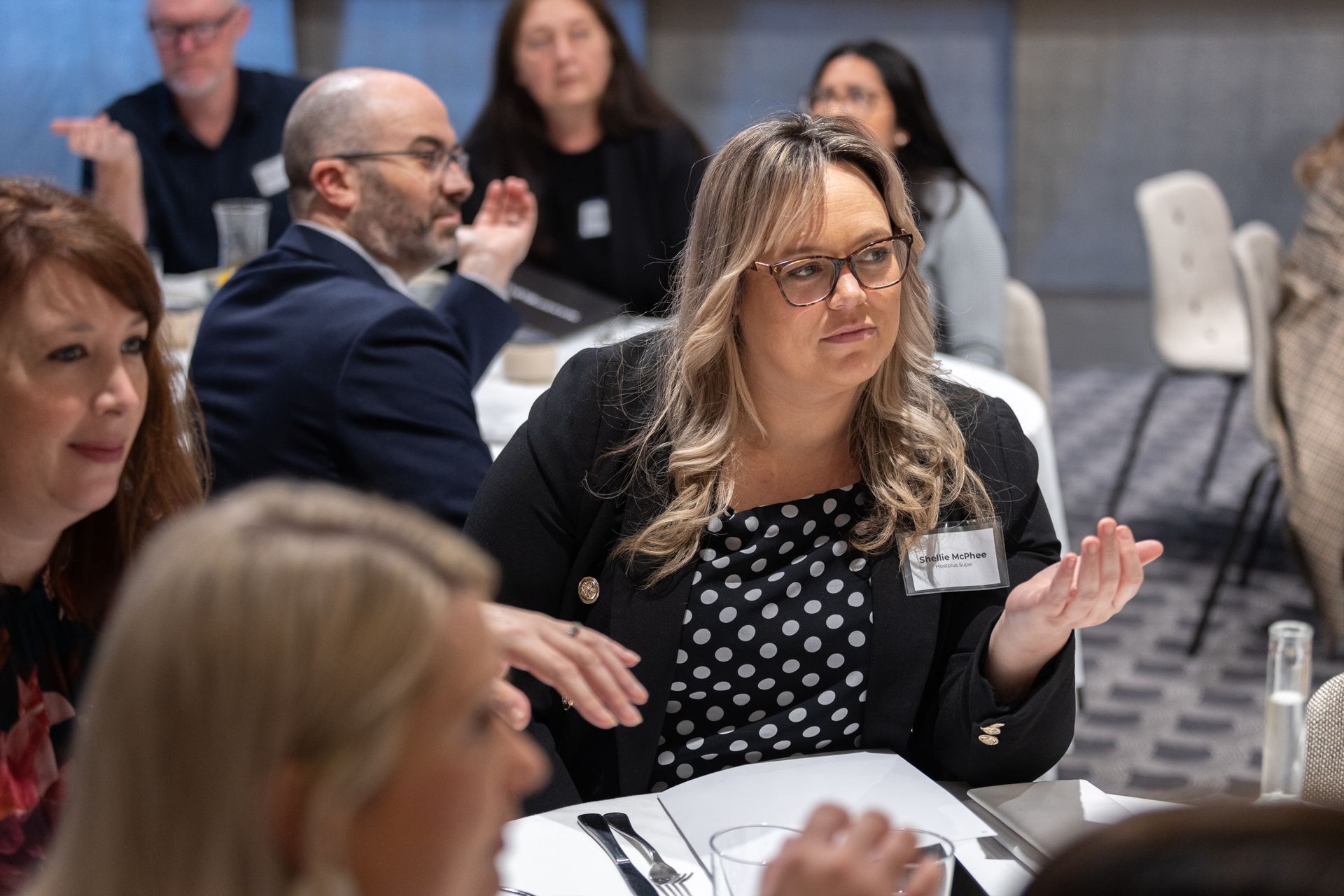 A woman is sitting at a table talking to a group of people.