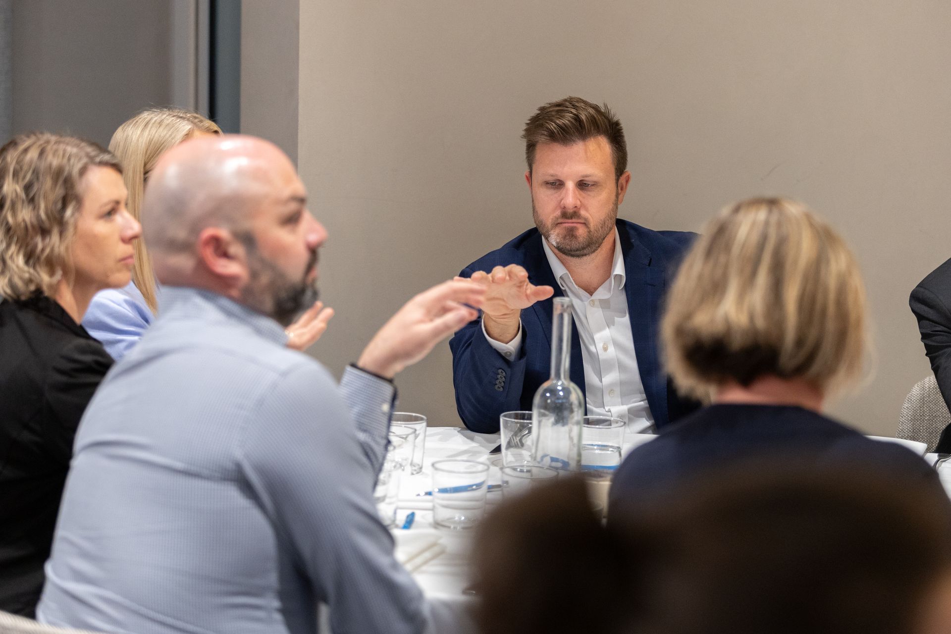 A group of people are sitting around a table talking to each other.