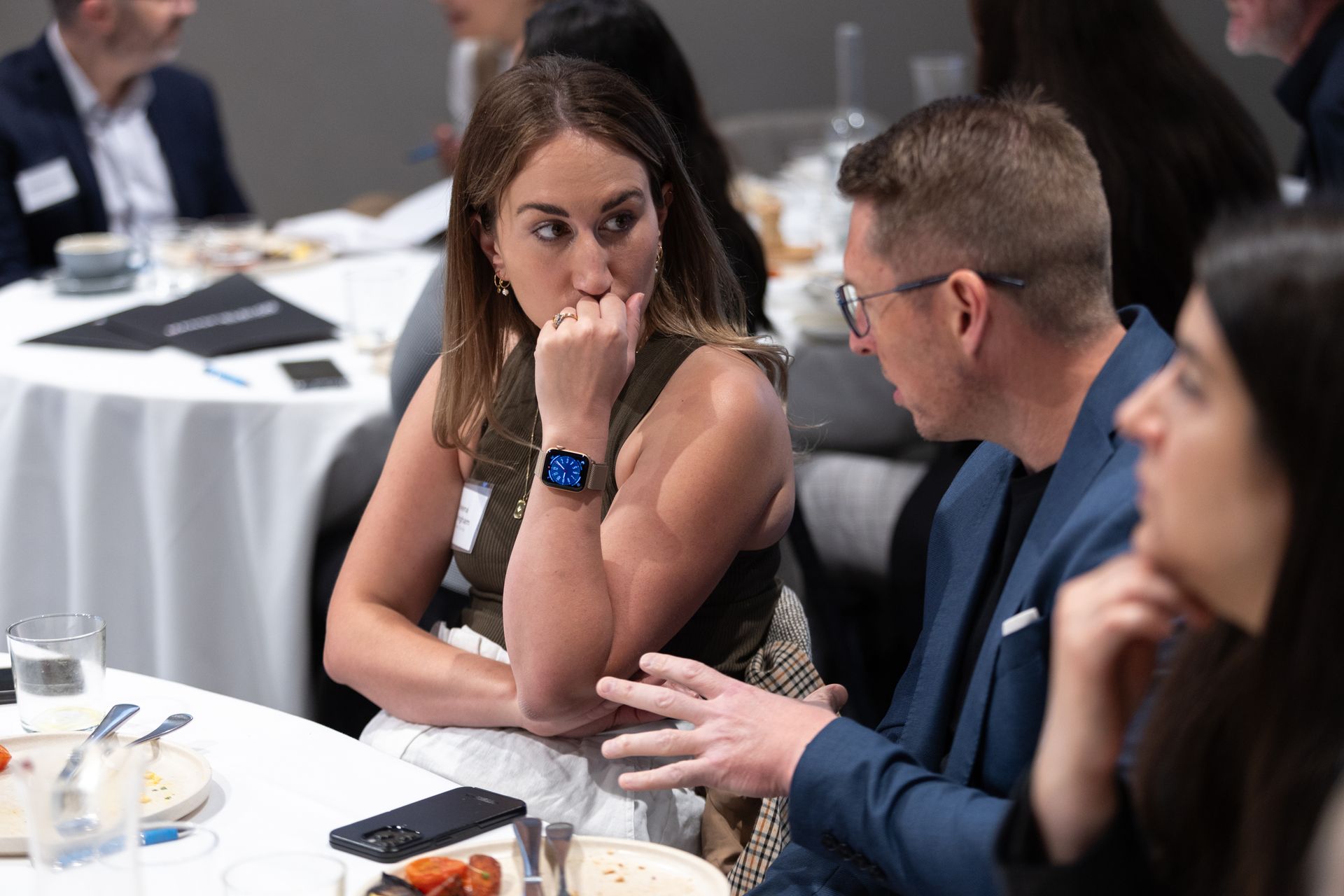 A group of people are sitting at a table talking to each other.