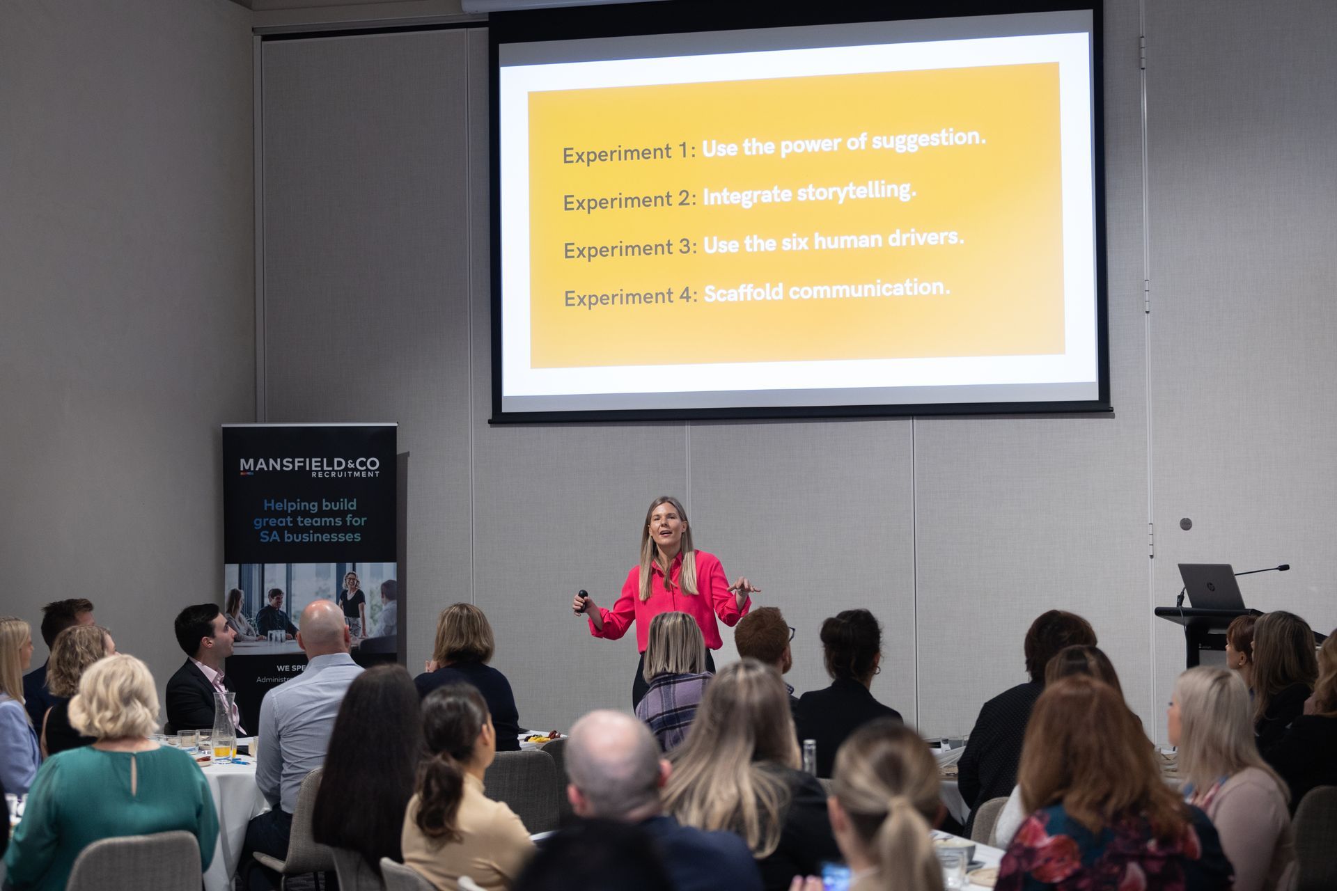 A woman is giving a presentation to a group of people at a conference.